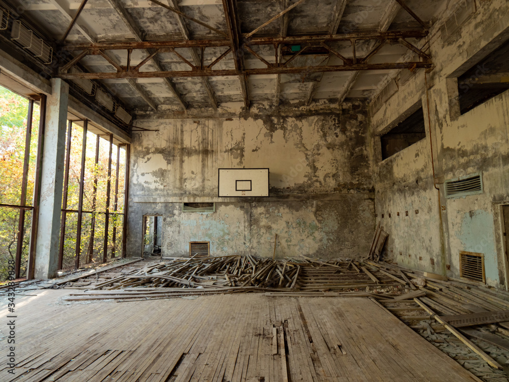 Abandoned empty gym in school in Pripyat near Chernobyl, Ukraine. The surrounding of the gym is overgrown with trees and bushes. Abandoned empty gym in school in Pripyat near Chernobyl, Ukraine. The surrounding of the gym is overgrown with trees and bushes.