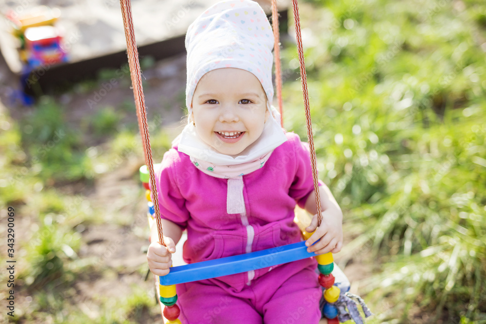 Happy little girl on swings in spring garden Happy little girl on swings in spring garden