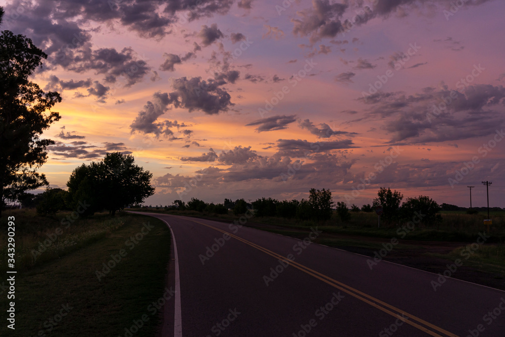 Empty road beneath a colorful sky during summer sunset
