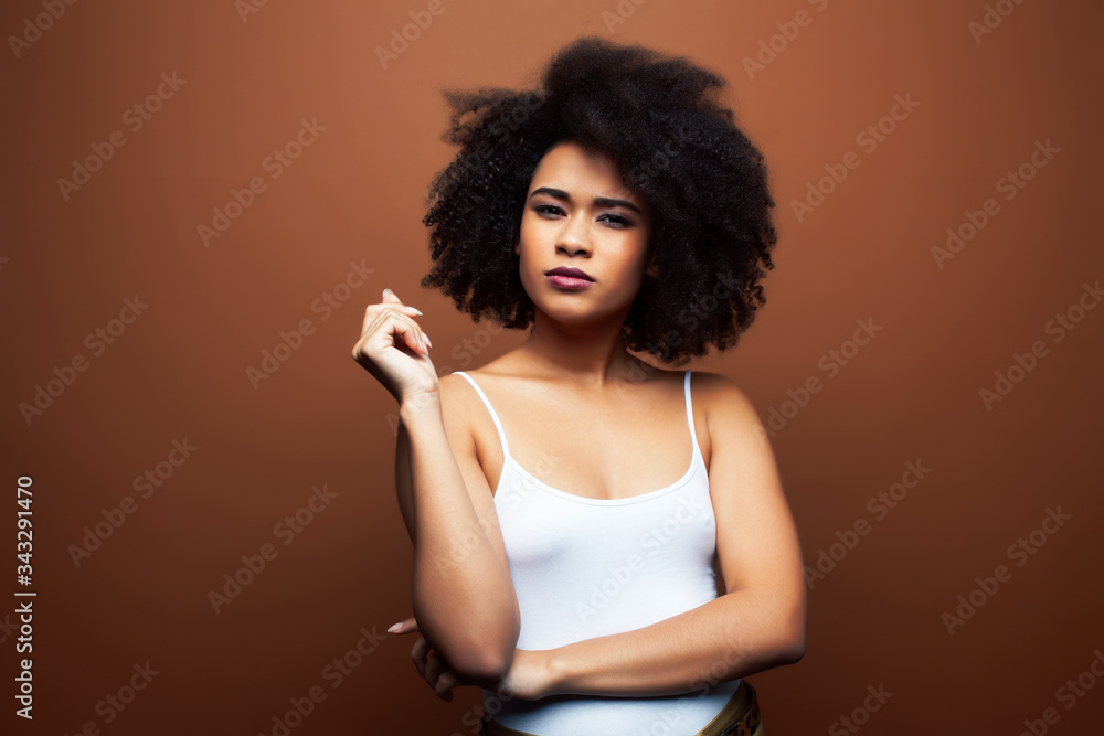 pretty young african american woman with curly hair posing cheerful gesturing on brown background, lifestyle people concept pretty young african american woman with curly hair posing cheerful gesturing on brown background, lifestyle people concept