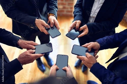 Group of business workers standing on a circle using smartphone together at the office.