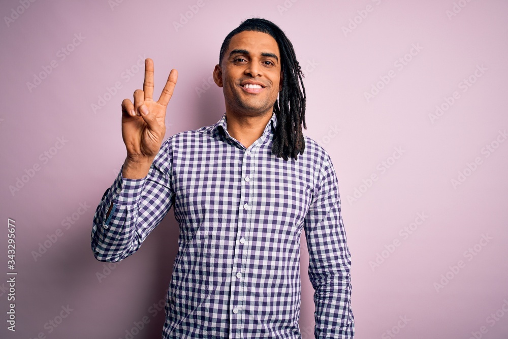 Young handsome african american afro man with dreadlocks wearing casual shirt showing and pointing up with fingers number two while smiling confident and happy. Young handsome african american afro man with dreadlocks wearing casual shirt showing and pointing up with fingers number two while smiling confident and happy.