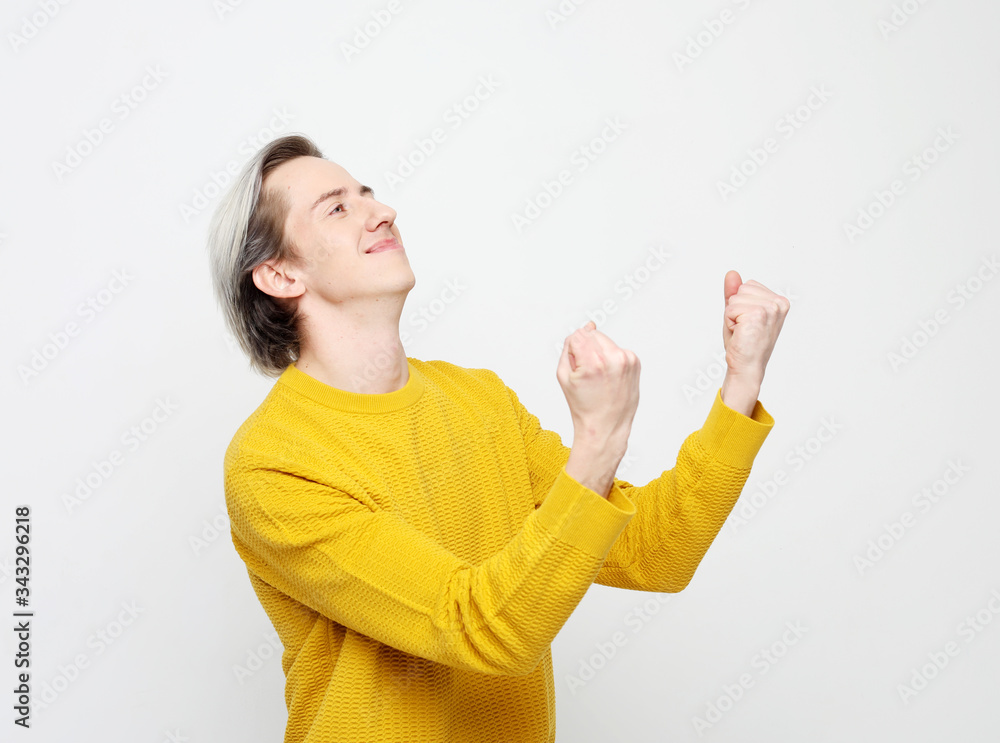 Win. Young handsome man wear yellow sweater with emotions on his face on white background Win. Young handsome man wear yellow sweater with emotions on his face on white background