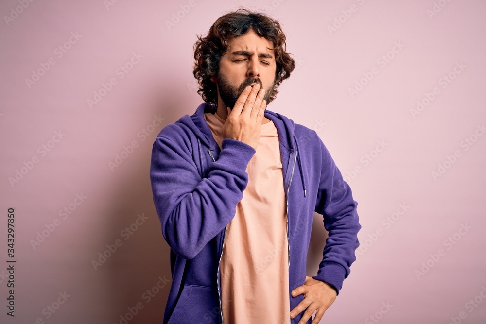 Young handsome sporty man with beard wearing casual sweatshirt over pink background bored yawning tired covering mouth with hand. Restless and sleepiness. Young handsome sporty man with beard wearing casual sweatshirt over pink background bored yawning tired covering mouth with hand. Restless and sleepiness.
