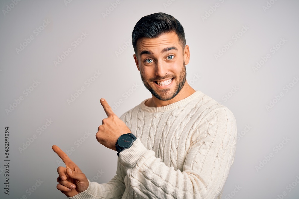 Young handsome man wearing casual sweater standing over isolated white background smiling and looking at the camera pointing with two hands and fingers to the side. Young handsome man wearing casual sweater standing over isolated white background smiling and looking at the camera pointing with two hands and fingers to the side.