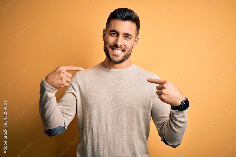 Young handsome man wearing casual sweater standing over isolated yellow background looking confident with smile on face, pointing oneself with fingers proud and happy. Young handsome man wearing casual sweater standing over isolated yellow background looking confident with smile on face, pointing oneself with fingers proud and happy.