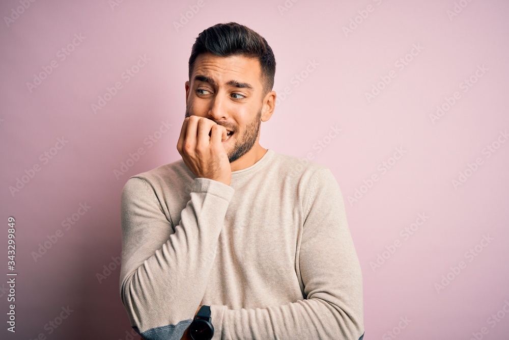Young handsome man wearing casual sweater standing over isolated pink background looking stressed and nervous with hands on mouth biting nails. Anxiety problem. Young handsome man wearing casual sweater standing over isolated pink background looking stressed and nervous with hands on mouth biting nails. Anxiety problem.
