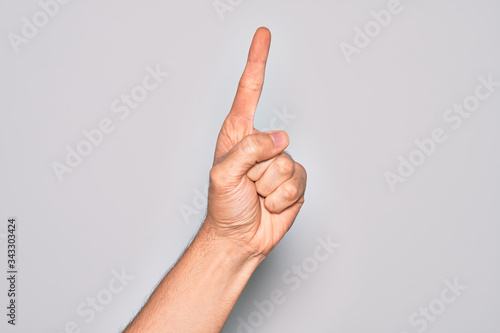 Hand of caucasian young man showing fingers over isolated white background counting number one using index finger, showing idea and understanding
