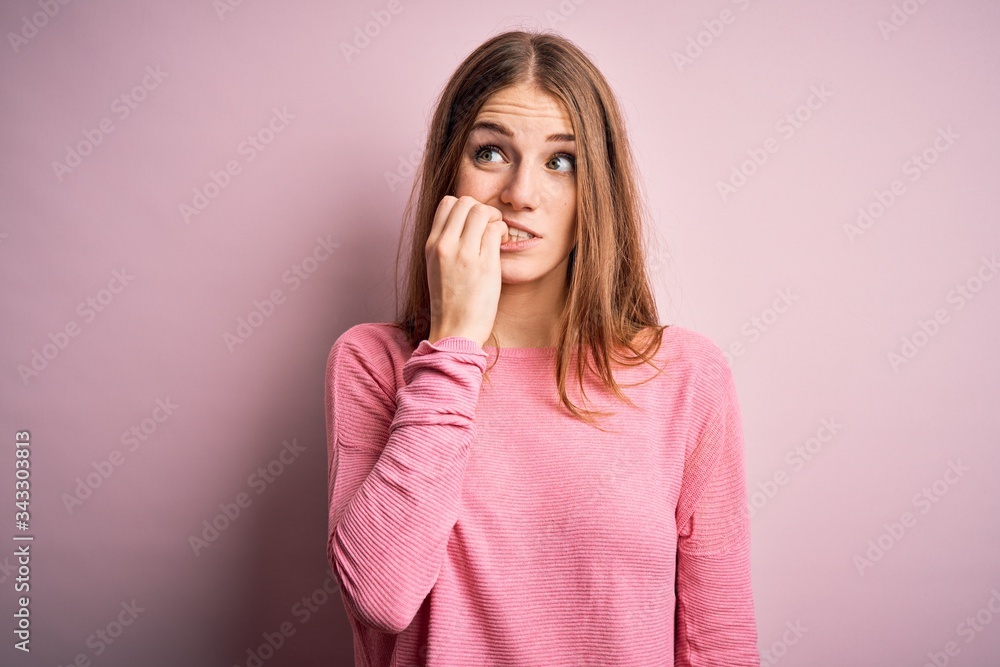 Young beautiful redhead woman wearing casual sweater over isolated pink background looking stressed and nervous with hands on mouth biting nails. Anxiety problem. Young beautiful redhead woman wearing casual sweater over isolated pink background looking stressed and nervous with hands on mouth biting nails. Anxiety problem.