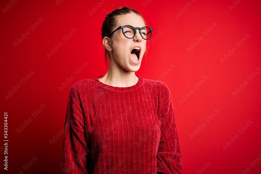 Young beautiful redhead woman wearing casual sweater over isolated red background angry and mad screaming frustrated and furious, shouting with anger. Rage and aggressive concept. Young beautiful redhead woman wearing casual sweater over isolated red background angry and mad screaming frustrated and furious, shouting with anger. Rage and aggressive concept.