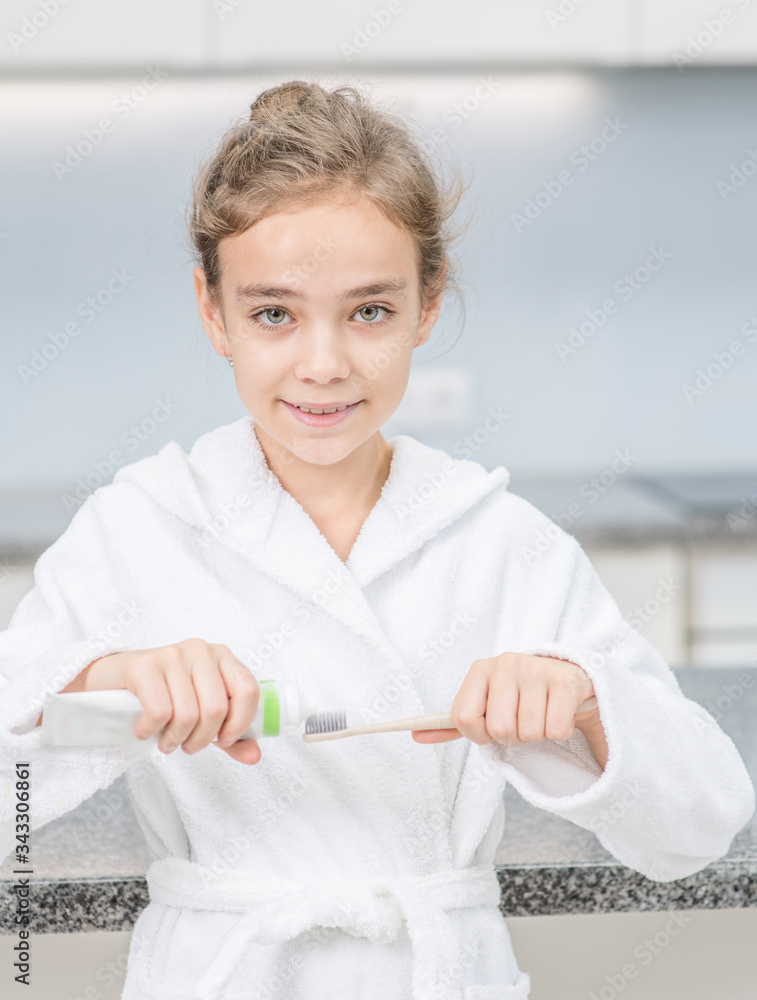 Smiling young girl squeezing toothpaste on a toothbrush in the bathroom at home Smiling young girl squeezing toothpaste on a toothbrush in the bathroom at home