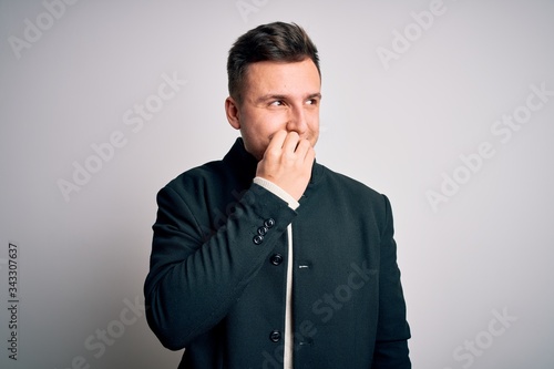 Young handsome business mas wearing elegant winter coat standing over isolated background looking stressed and nervous with hands on mouth biting nails. Anxiety problem.