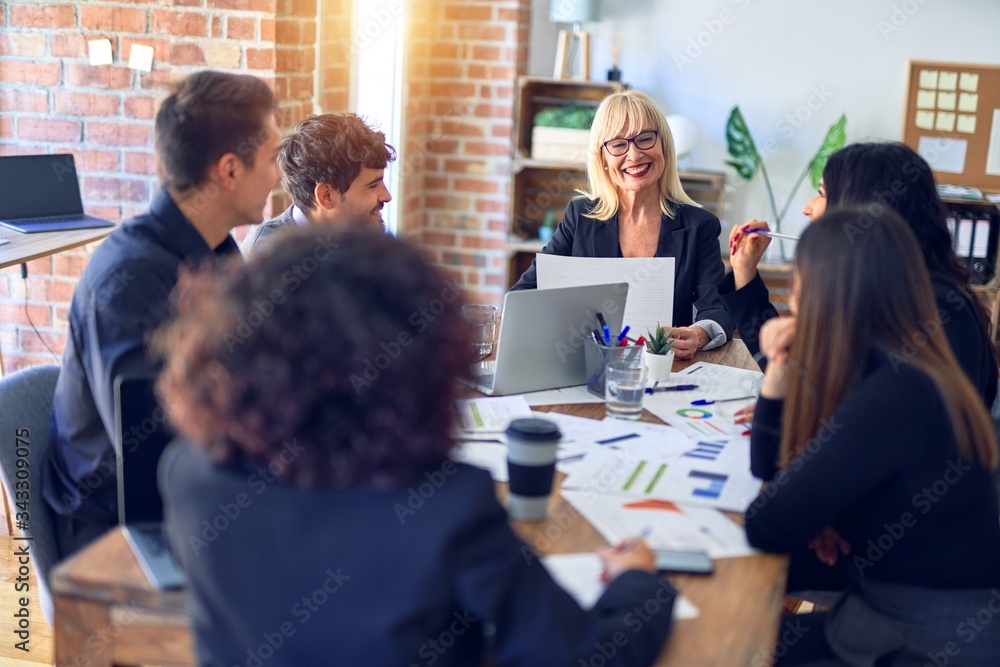 Group of business workers smiling happy and confident. Working together with smile on face using laptop and speaking at the office Group of business workers smiling happy and confident. Working together with smile on face using laptop and speaking at the office