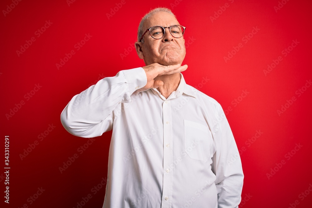 Middle age handsome hoary man wearing casual shirt and glasses over red background cutting throat with hand as knife, threaten aggression with furious violence Middle age handsome hoary man wearing casual shirt and glasses over red background cutting throat with hand as knife, threaten aggression with furious violence