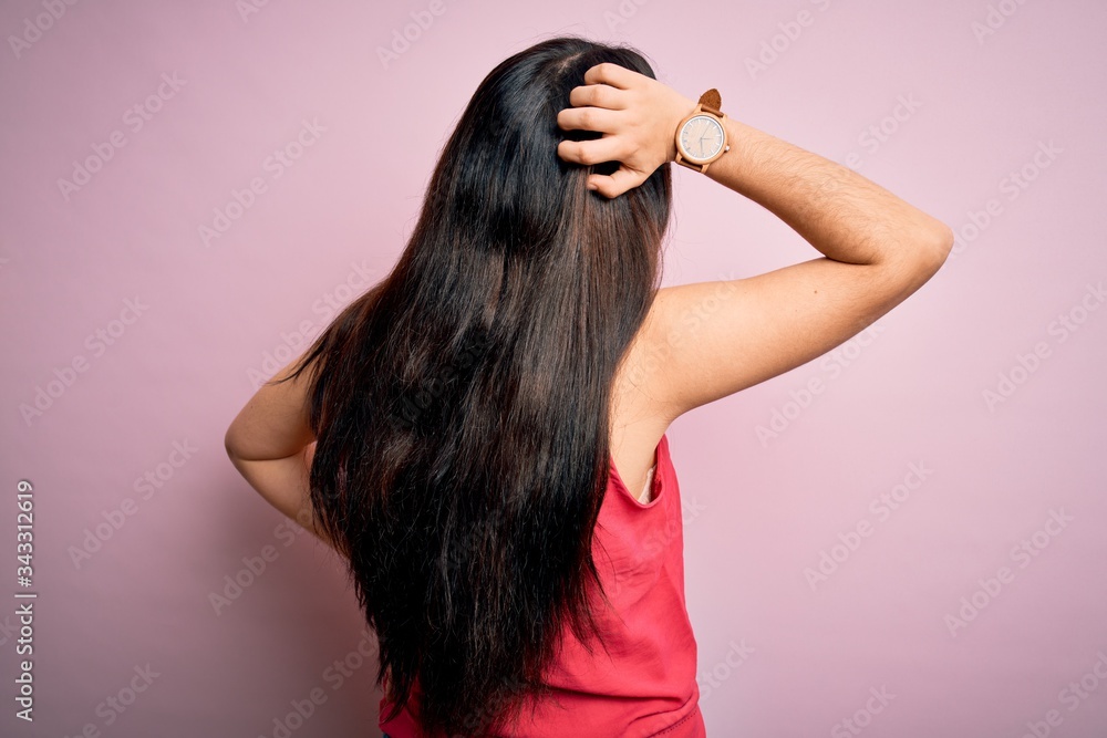 Fototapeta premium Young brunette woman wearing casual summer shirt over pink isolated background Backwards thinking about doubt with hand on head