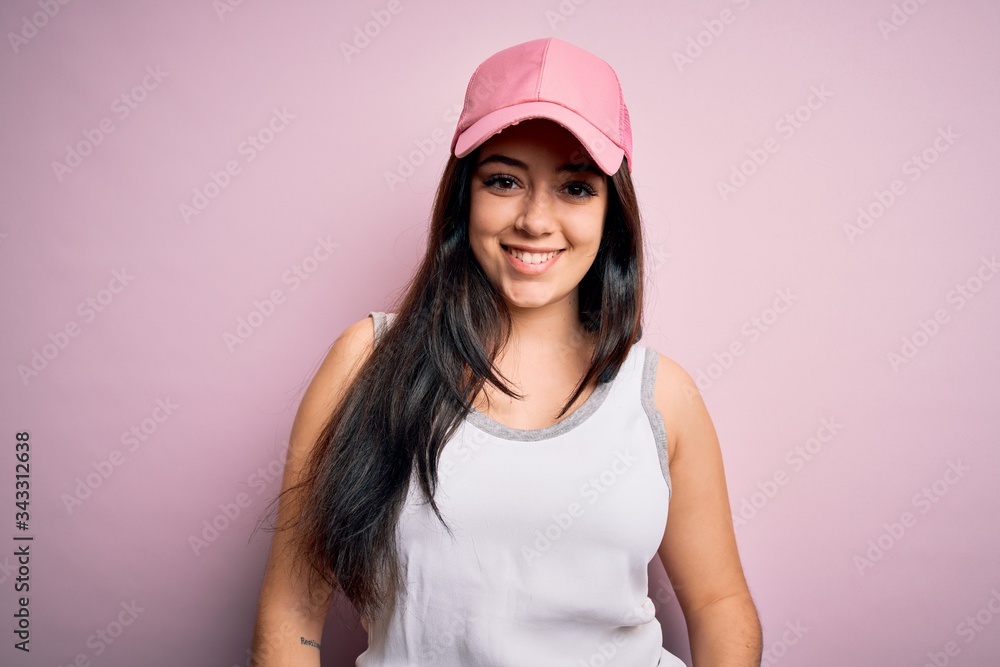 Young brunette woman wearing casual sport cap over pink background with a happy and cool smile on face. Lucky person. Young brunette woman wearing casual sport cap over pink background with a happy and cool smile on face. Lucky person.