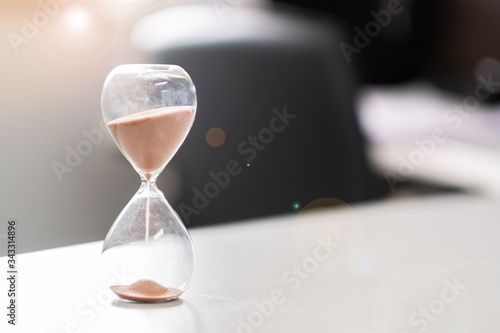Hourglass on table office with copy space, Sand flowing through the bulb of Sandglass measuring the passing time. countdown, deadline, Life time and Retirement concept