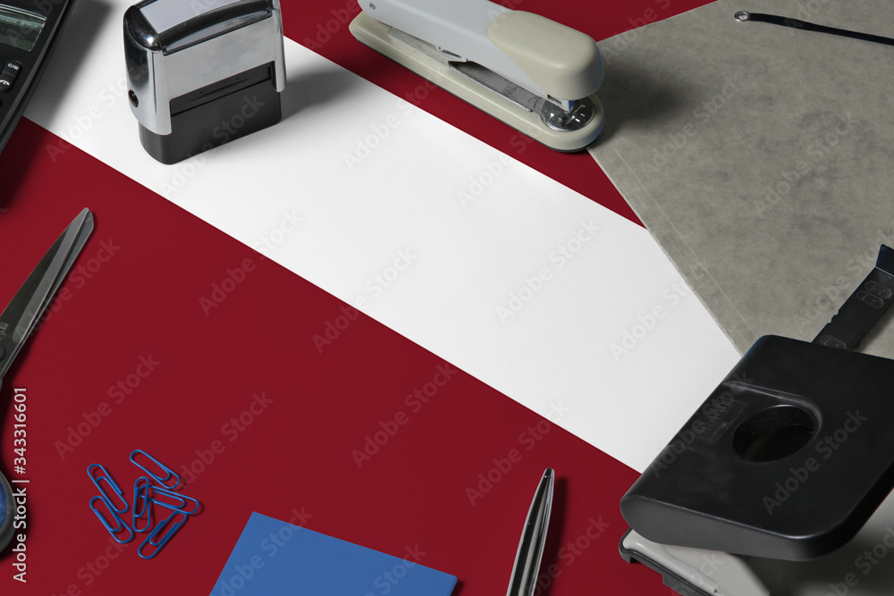 Latvia flag with office clerk workplace background. National stationary concept with office tools. Latvia flag with office clerk workplace background. National stationary concept with office tools.