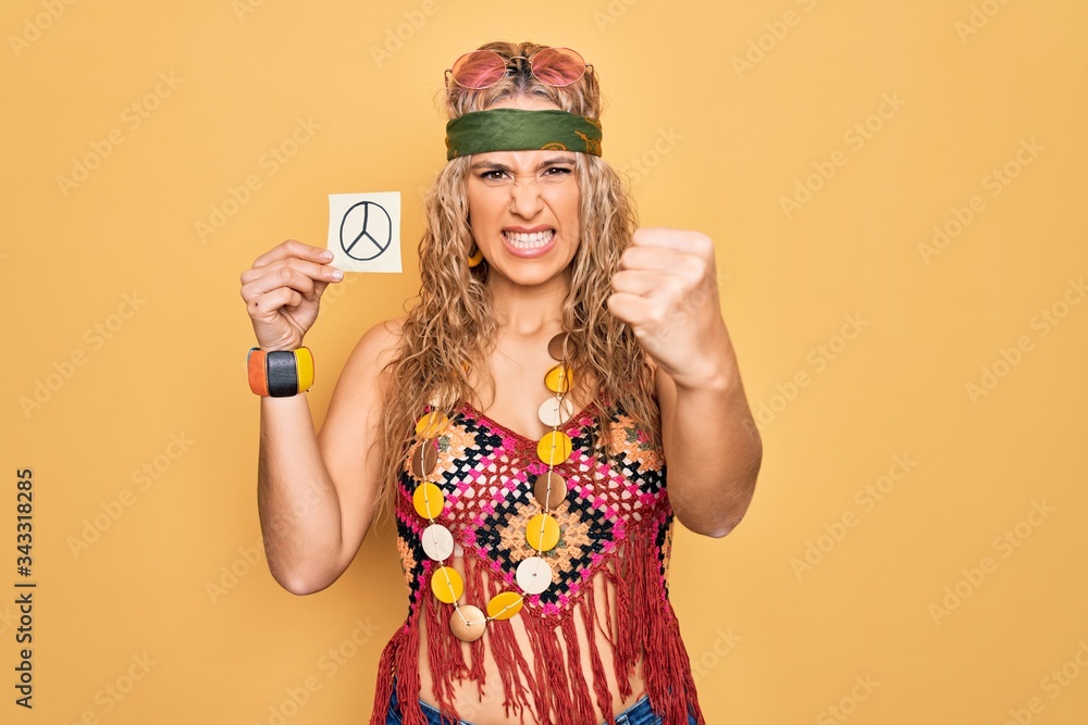 Blonde hippie woman wearing sunglasses and accessories holding reminder with peace symbol annoyed and frustrated shouting with anger, yelling crazy with anger and hand raised Blonde hippie woman wearing sunglasses and accessories holding reminder with peace symbol annoyed and frustrated shouting with anger, yelling crazy with anger and hand raised