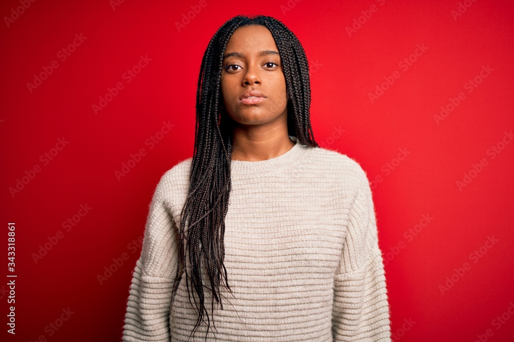 Fototapeta premium Young african american woman wearing casual winter sweater over red isolated background Relaxed with serious expression on face. Simple and natural looking at the camera.