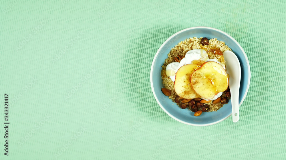 Healthy breakfast bowl with oats, spices, yogurt, fresh fruit, nuts, honey and high fiber LSA on modern green background. Top view flatlay with negative copy space. Healthy breakfast bowl with oats, spices, yogurt, fresh fruit, nuts, honey and high fiber LSA on modern green background. Top view flatlay with negative copy space.