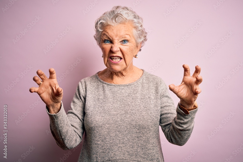 Senior beautiful woman wearing casual t-shirt standing over isolated pink background smiling funny doing claw gesture as cat, aggressive and sexy expression Senior beautiful woman wearing casual t-shirt standing over isolated pink background smiling funny doing claw gesture as cat, aggressive and sexy expression