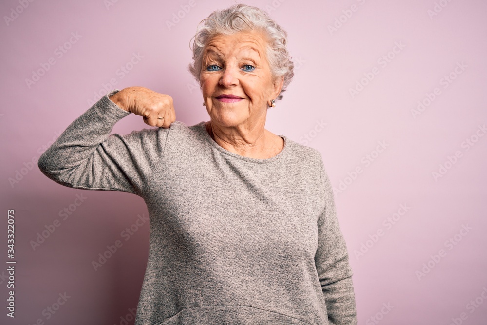 Senior beautiful woman wearing casual t-shirt standing over isolated pink background Strong person showing arm muscle, confident and proud of power Senior beautiful woman wearing casual t-shirt standing over isolated pink background Strong person showing arm muscle, confident and proud of power