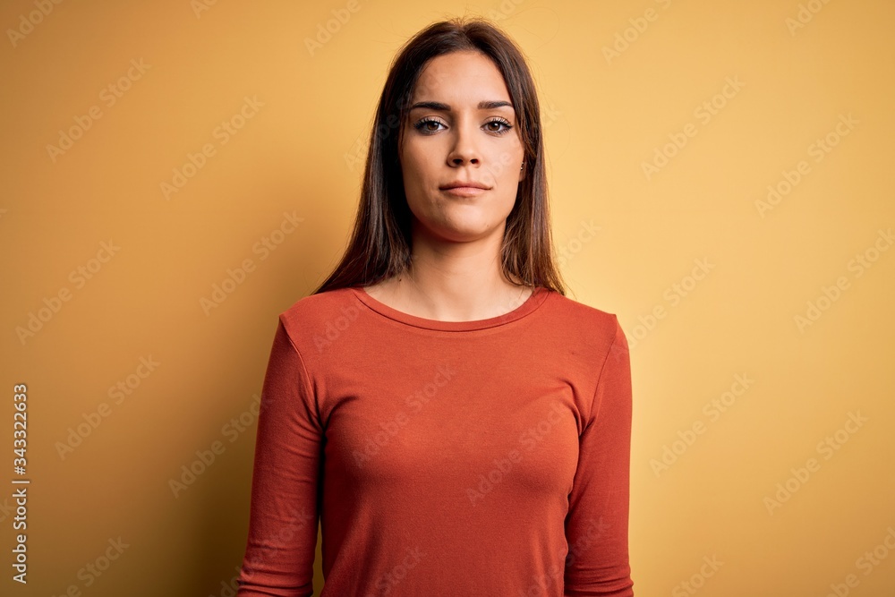 Obraz premium Young beautiful brunette woman wearing casual t-shirt standing over yellow background looking sleepy and tired, exhausted for fatigue and hangover, lazy eyes in the morning.