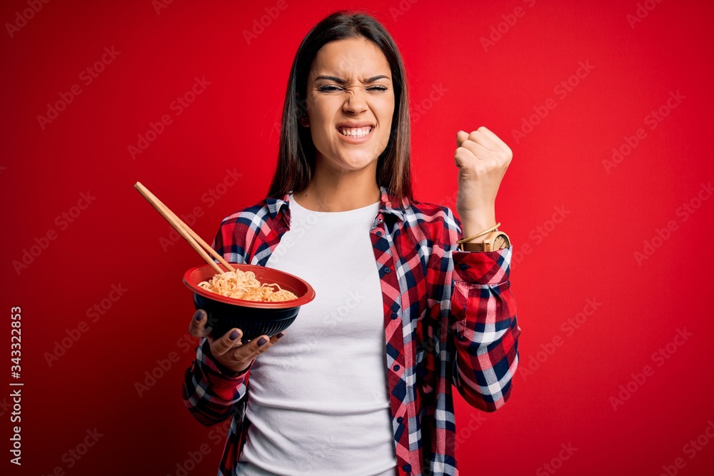Young beautiful brunette woman eating noodles using chopsticks over red background annoyed and frustrated shouting with anger, crazy and yelling with raised hand, anger concept Young beautiful brunette woman eating noodles using chopsticks over red background annoyed and frustrated shouting with anger, crazy and yelling with raised hand, anger concept