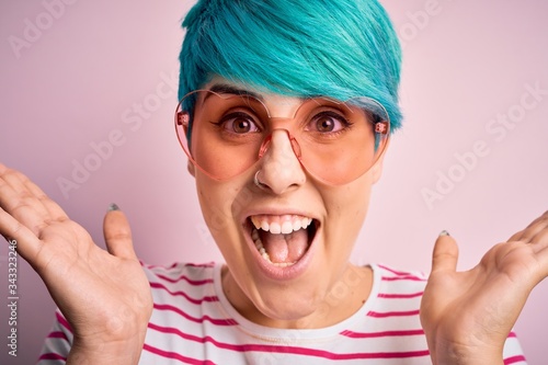 Fényképezés Young beautiful woman with blue fashion hair wearing fanny glasses with hearts v
