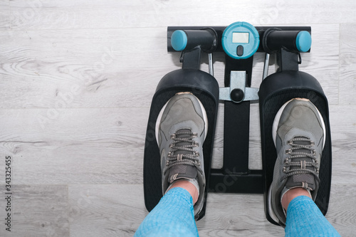 Feet of woman exercising on a twister  stepper. Digital display, keeping fit at home.