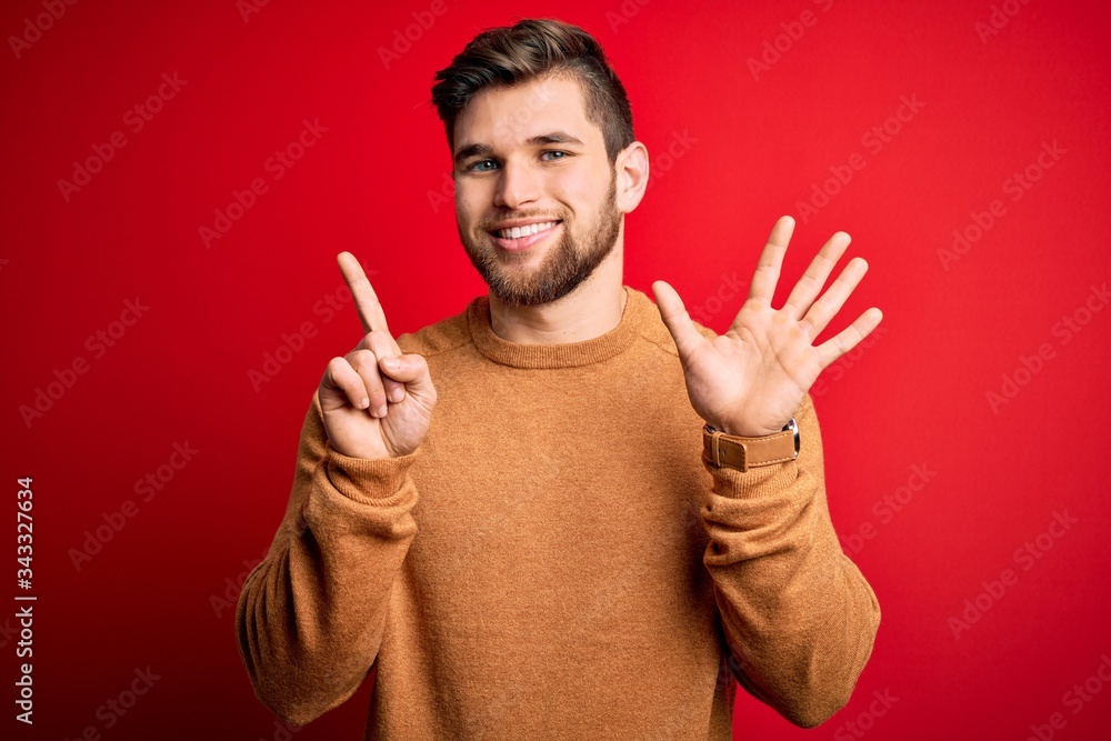 Young blond man with beard and blue eyes wearing casual sweater over red background showing and pointing up with fingers number six while smiling confident and happy. Young blond man with beard and blue eyes wearing casual sweater over red background showing and pointing up with fingers number six while smiling confident and happy.