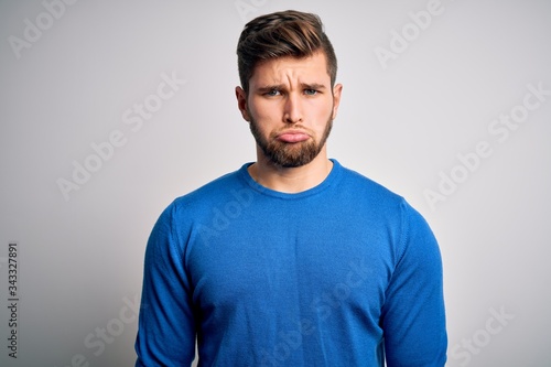 Young handsome blond man with beard and blue eyes wearing casual sweater depressed and worry for distress, crying angry and afraid. Sad expression. © Krakenimages.com