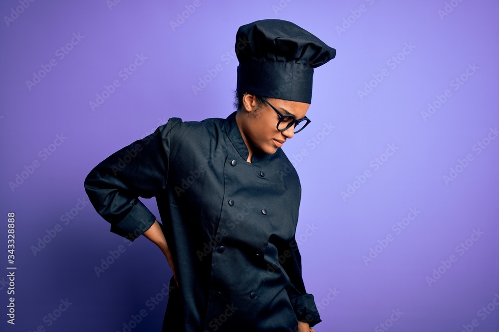 Young african american chef girl wearing cooker uniform and hat over purple background Suffering of backache, touching back with hand, muscular pain Young african american chef girl wearing cooker uniform and hat over purple background Suffering of backache, touching back with hand, muscular pain