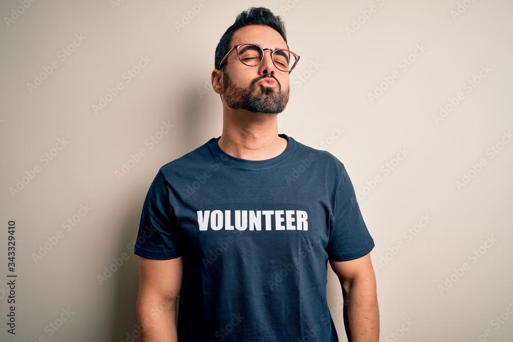 Handsome man with beard wearing t-shirt with volunteer message over white background looking at the camera blowing a kiss on air being lovely and sexy. Love expression. Handsome man with beard wearing t-shirt with volunteer message over white background looking at the camera blowing a kiss on air being lovely and sexy. Love expression.