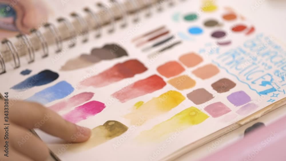 teenager pointing to colors in sketchbook with painted swatches teenager pointing to colors in sketchbook with painted swatches