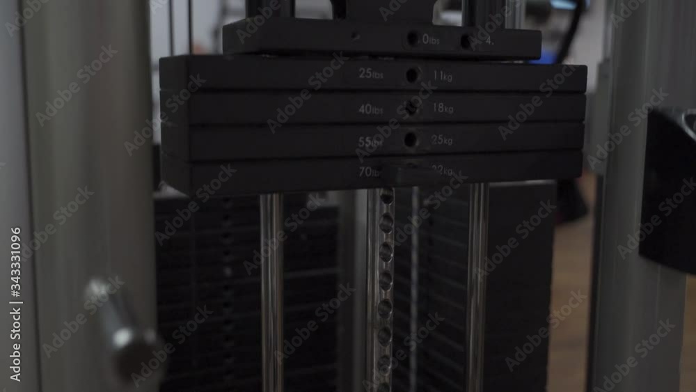 Close up weights moving up and down at device while exercise training in gym studio, camera moving with the weights Close up weights moving up and down at device while exercise training in gym studio, camera moving with the weights
