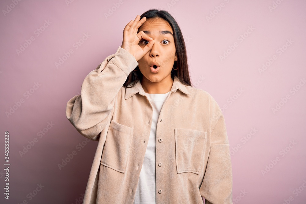 Young beautiful asian woman wearing casual shirt standing over pink background doing ok gesture shocked with surprised face, eye looking through fingers. Unbelieving expression. Young beautiful asian woman wearing casual shirt standing over pink background doing ok gesture shocked with surprised face, eye looking through fingers. Unbelieving expression.