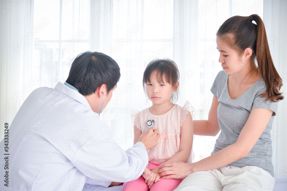 Asian doctor examining a girl body by stethoscope at hospital and girl's mother sitting beside her daughter . Asian doctor examining a girl body by stethoscope at hospital and girl's mother sitting beside her daughter .