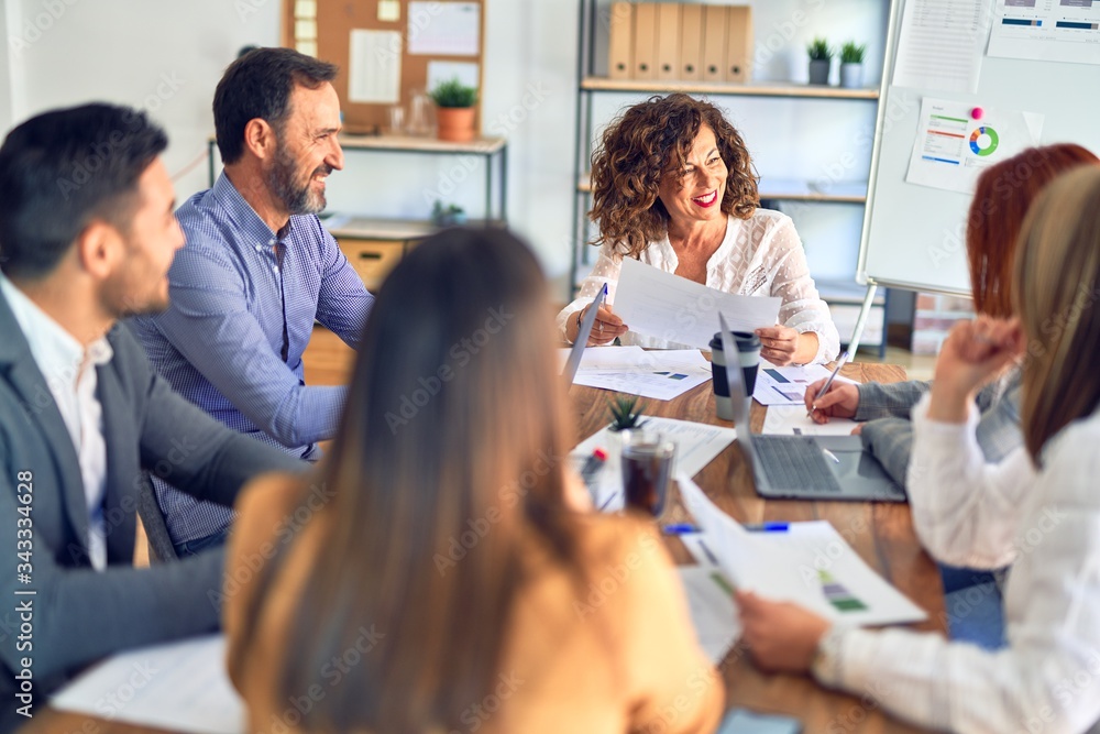 Group of business workers working together. Sitting on desk using laptop reading documents at the office Group of business workers working together. Sitting on desk using laptop reading documents at the office
