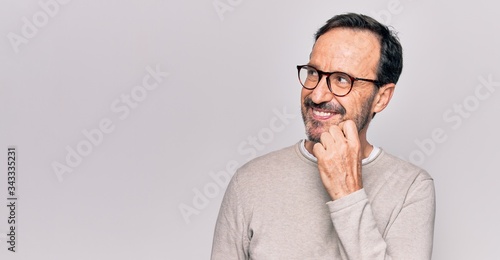 Obraz na plátně Middle age handsome man wearing casual sweater and glasses over isolated white b