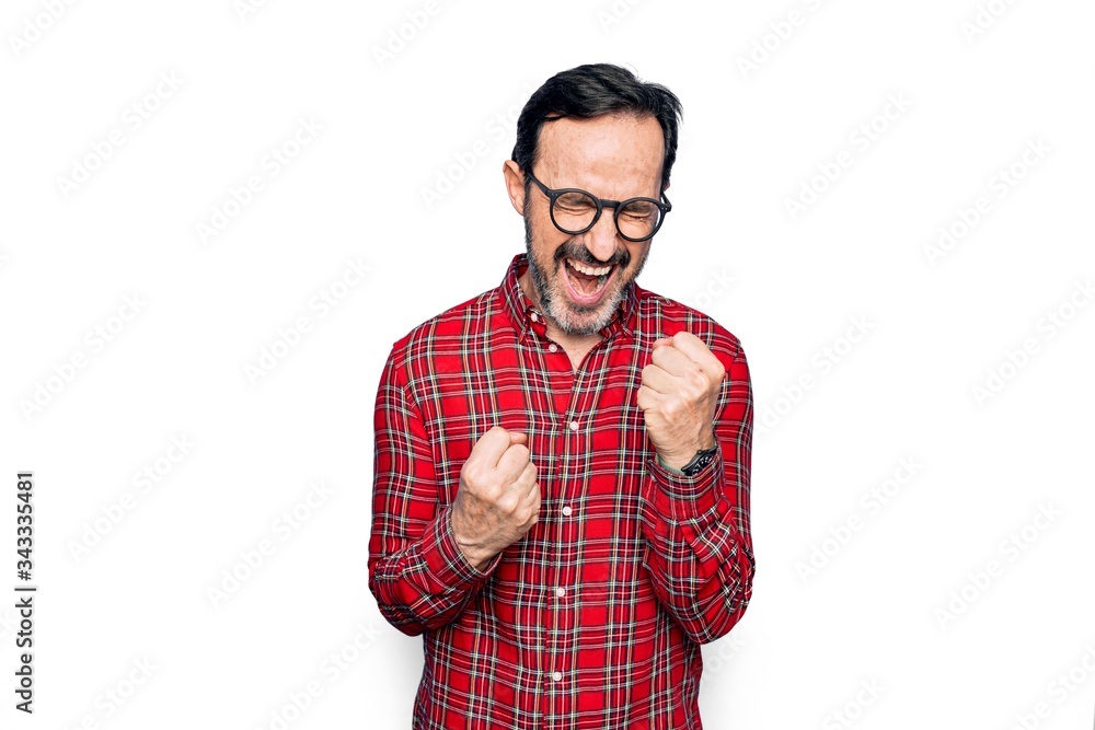 Middle age handsome man wearing casual shirt and glasses over isolated white background celebrating surprised and amazed for success with arms raised and eyes closed Middle age handsome man wearing casual shirt and glasses over isolated white background celebrating surprised and amazed for success with arms raised and eyes closed