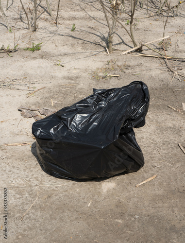 black plastic trash bag on the ground. The concept of ecology