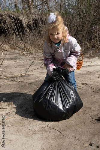 a little girl holds a garbage bag on nature. concept -ecology