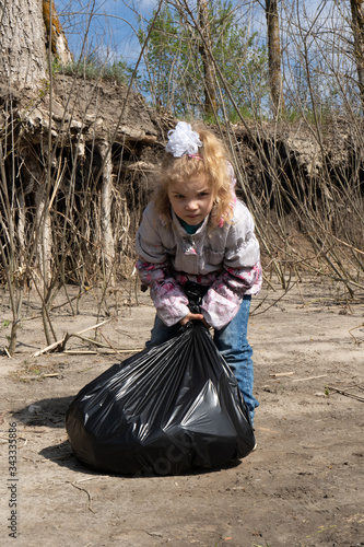 a little girl holds a garbage bag .  ecology