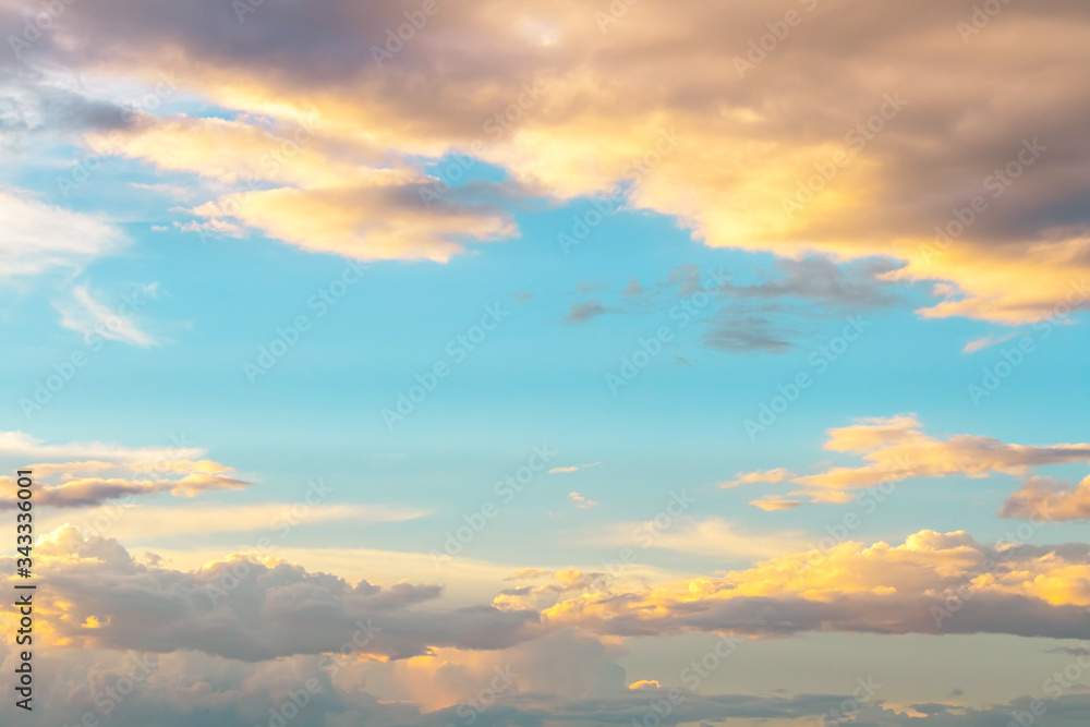 Fototapeta premium soft yellow light in light blue sky with fluffy clouds