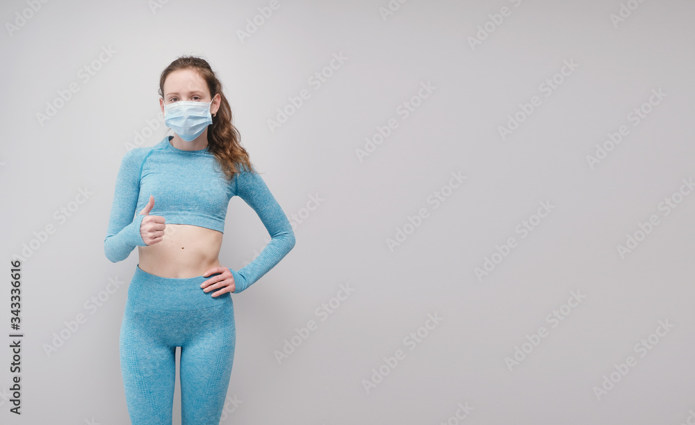 © reddish - Fitness girl wearing medicine mask in fitness costume isolated on grey costume. Training during quarantine, cover 19, corona virus. © reddish - Fitness girl wearing medicine mask in fitness costume isolated on grey costume. Training during quarantine, cover 19, corona virus.