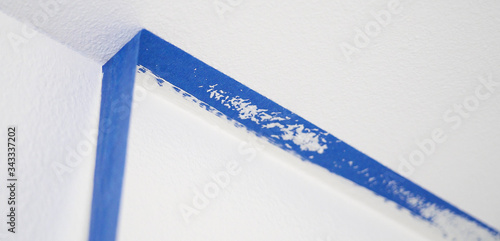 Removing masking blue tape from ceiling.