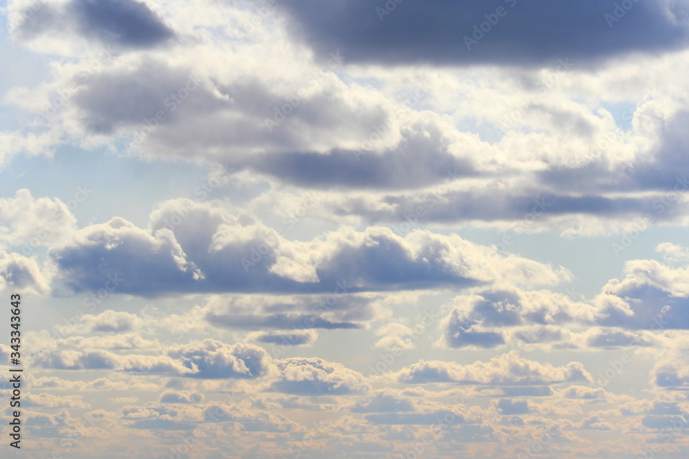 Obraz premium Clouds in the blue sky at sunset or dawn backlit by the sun. Place for text and design.