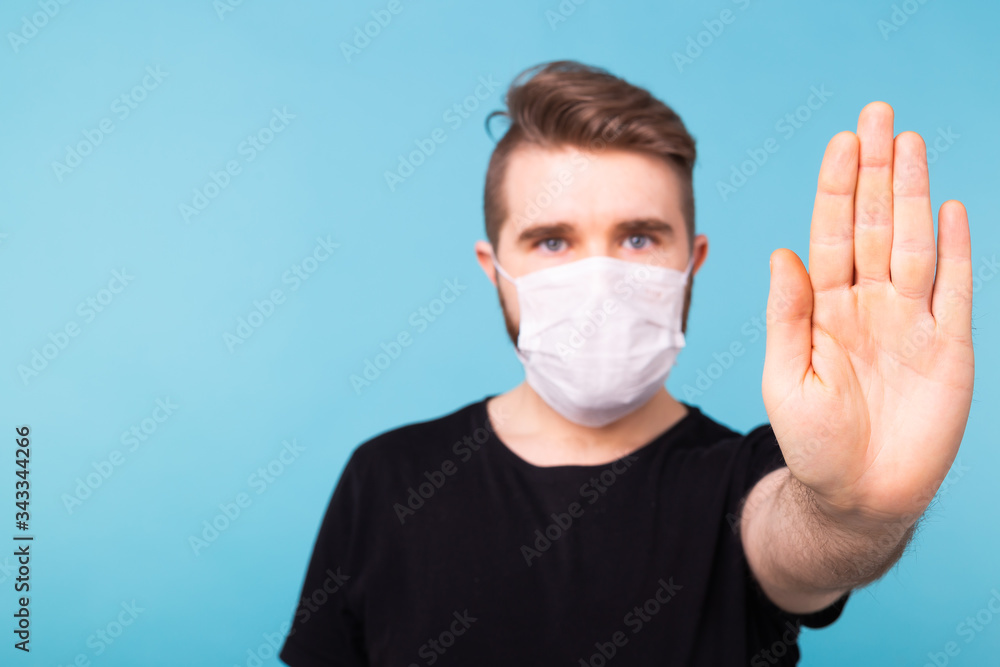 Handsome man showing gesture stop. Photo of healthy man wears protective mask against infectious diseases and flu. Health care, covid-19 and coronavirus concept. Handsome man showing gesture stop. Photo of healthy man wears protective mask against infectious diseases and flu. Health care, covid-19 and coronavirus concept.